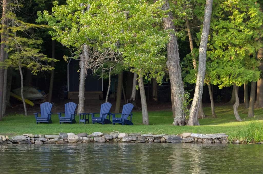 20 Top Airbnb Cottages in Muskoka for an Epic Getaway 44 View of Lake Rosseau from cottage with dark blue Muskoka chairs.