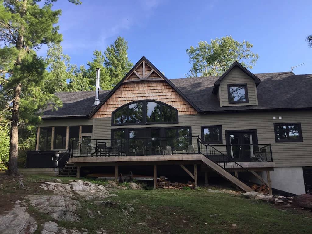 20 Top Airbnb Cottages in Muskoka for an Epic Getaway 24 New Luxury Cottage exterior view. Olive green cottage with oak shakers and a large wrap around porch.