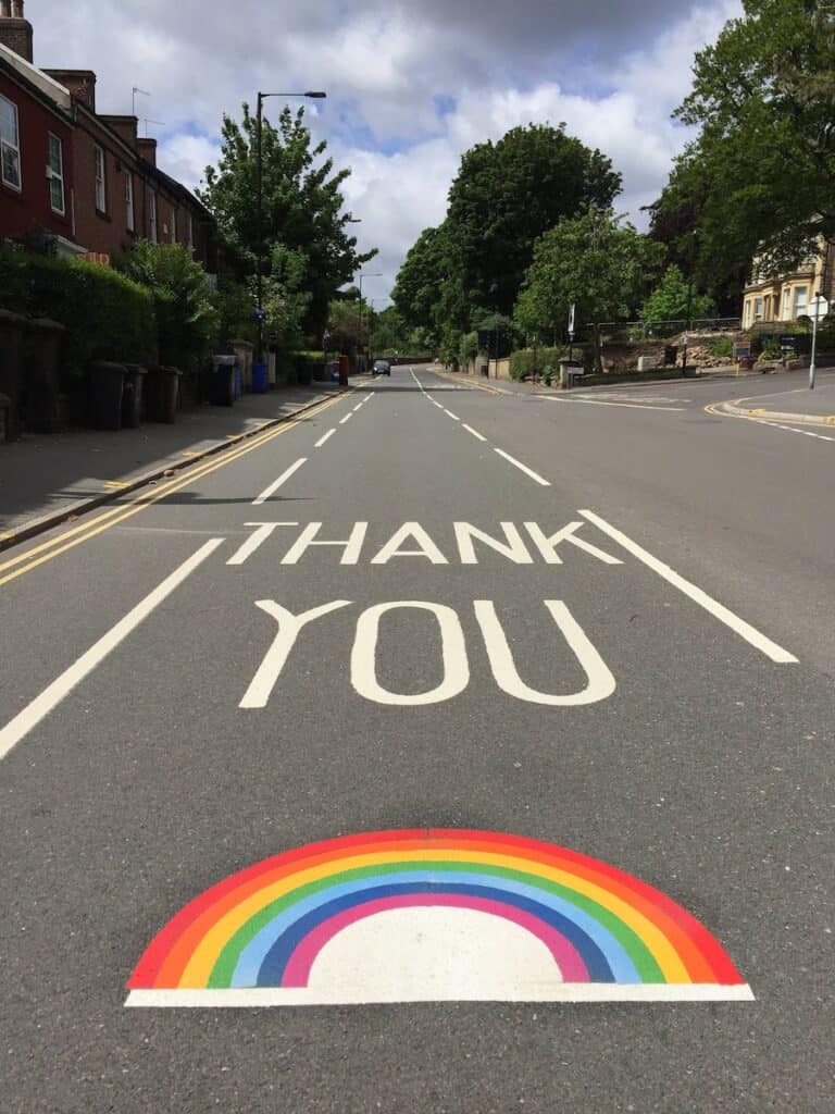 How to Say Thank You in 100 Different Languages 8 Thank you written in white paint on a street with a rainbow painted beneath it.