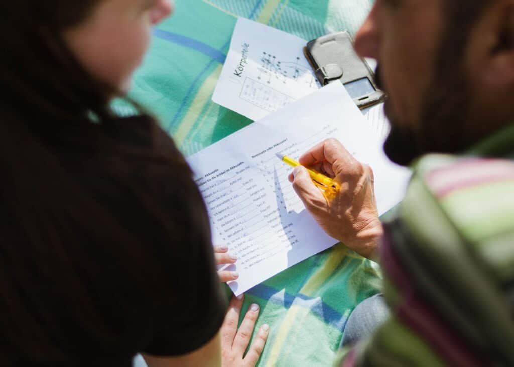 How to Say How Are You in 100 Different Languages 2 Language tutor teaching a student how to say how are you and other phrases in different languages with homework on a patchwork blanket.