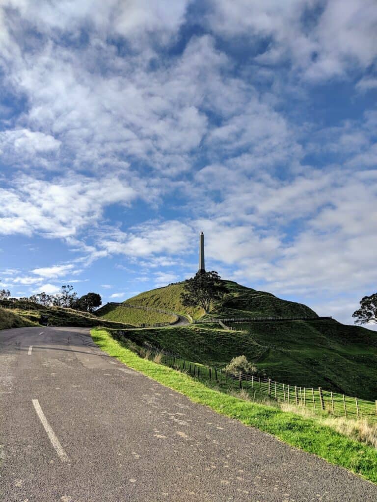 19 Pros and Cons of Living in Auckland NZ 4 Mount Eden in Auckland where you can overlook the city. Obelisk on a green grassy hill.