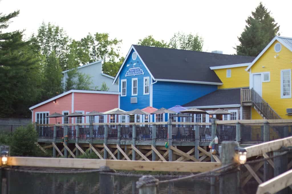 15 Best Cities to Live in Canada in 2024 (Local Tips!) 13 Beautiful bright coloured houses in Moncton along the docks. A pink, blue and yellow sided house sit next to each other on the pier overlooking the Bay of Fundy.
