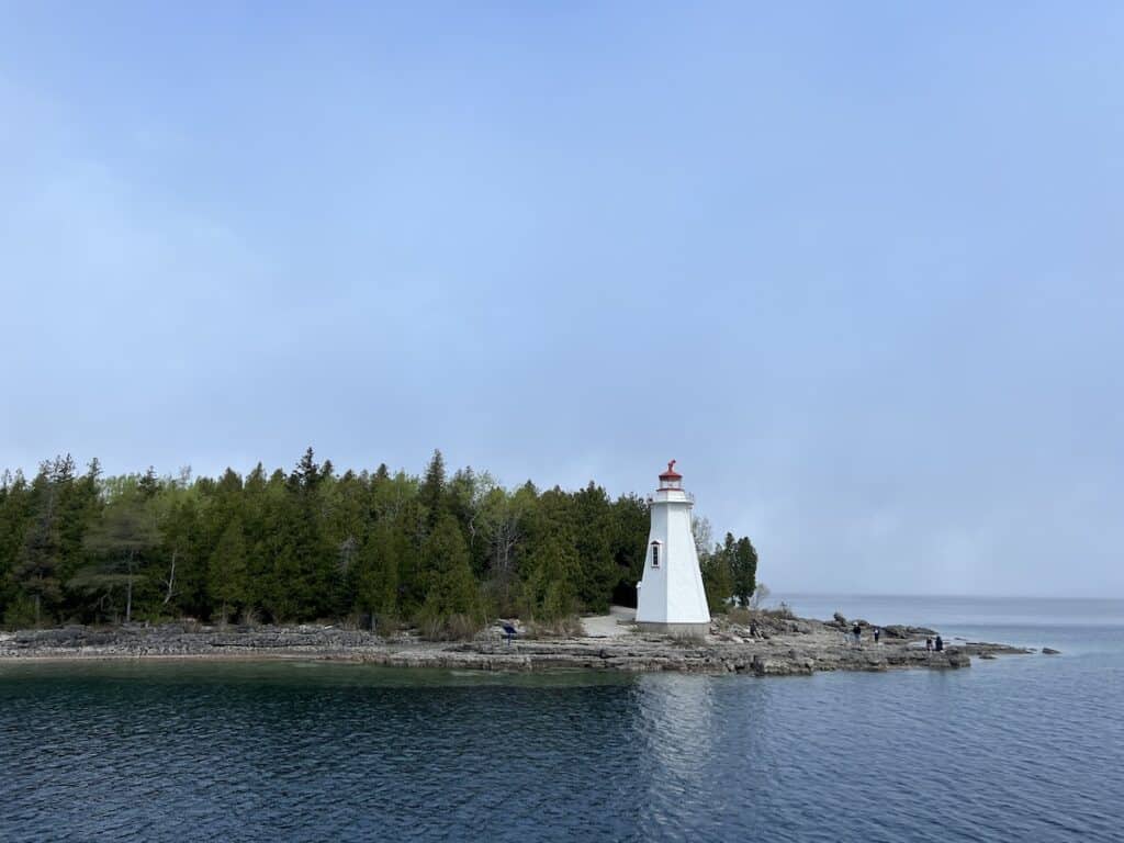 25 Jaw-Dropping Things to Do Tobermory, Ontario 9 Big Tub Lighthouse. White lighthouse with red detailing on the rocky shores of Big Tub Harbour in Tobermory.