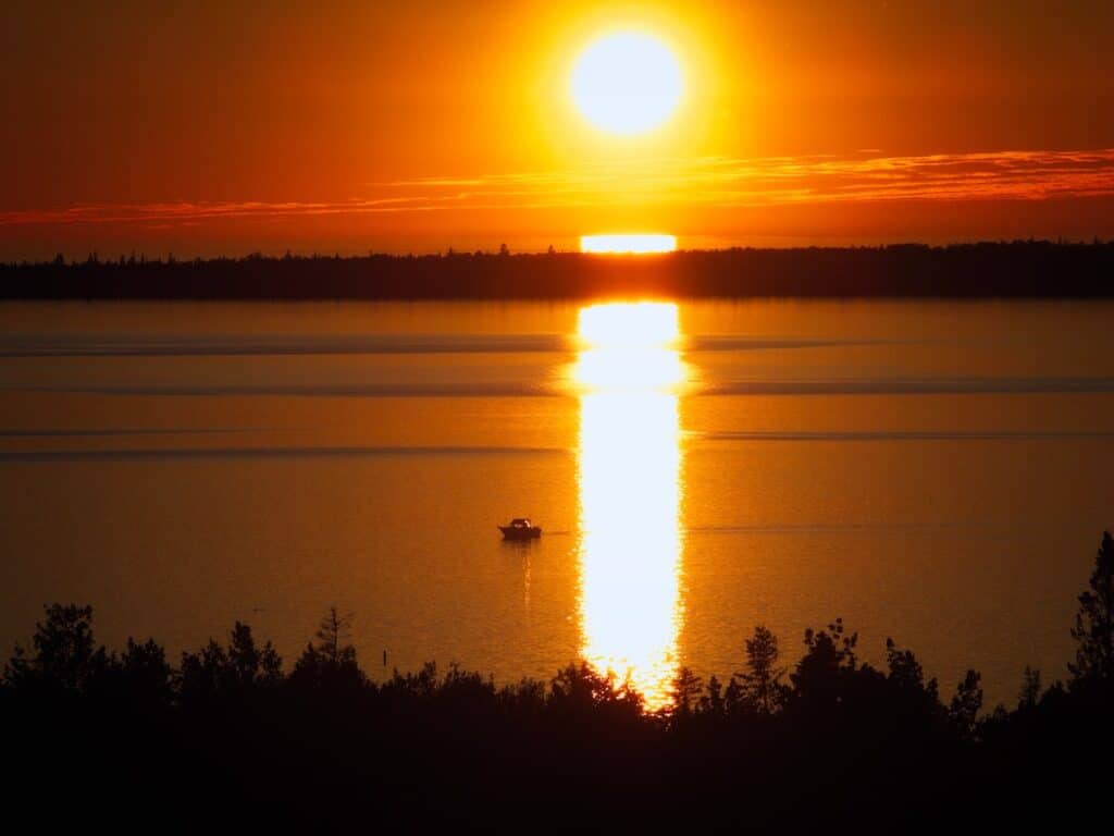 25 Jaw-Dropping Things to Do Tobermory, Ontario 10 Sunset with red and orange tones over the Lake Huron with boats on the water.