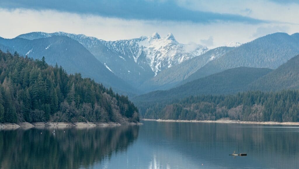 37 Amazing Vancouver Bucket List Things to Do 7 View of Whistler's white capped top from a lake with pine tree islands in the foreground.