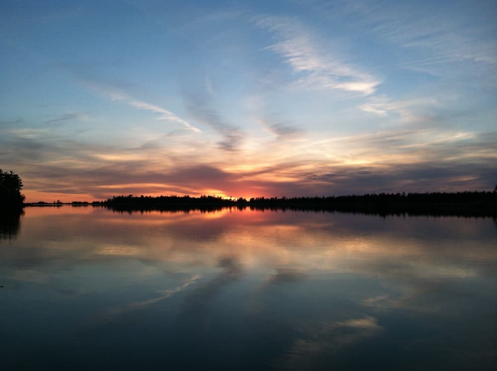 Michigan to Canada Drive: Best Places to Stop in Canada 6 Red sunset over Georgian Bay's clear waters on a still day. Shadowy silhouettes of the forests.