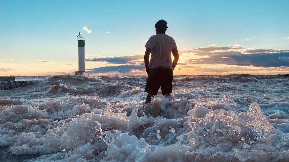 Michigan to Canada Drive: Best Places to Stop in Canada 5 Man playing in the surf of Lake Huron in Grand Bend beside a dock marker.