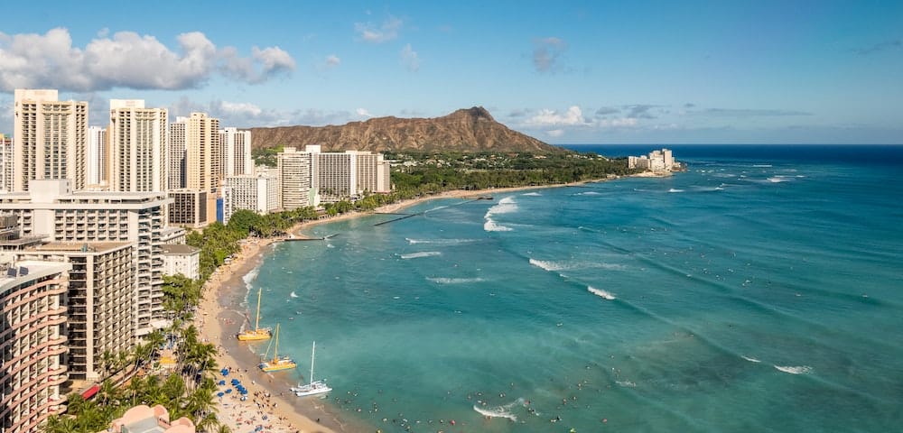 29 Pros and Cons of Living in Hawaii From an Expat 2 Beach in Honolulu with high rise buildings before the mountains and a turquoise ocean in Hawaii