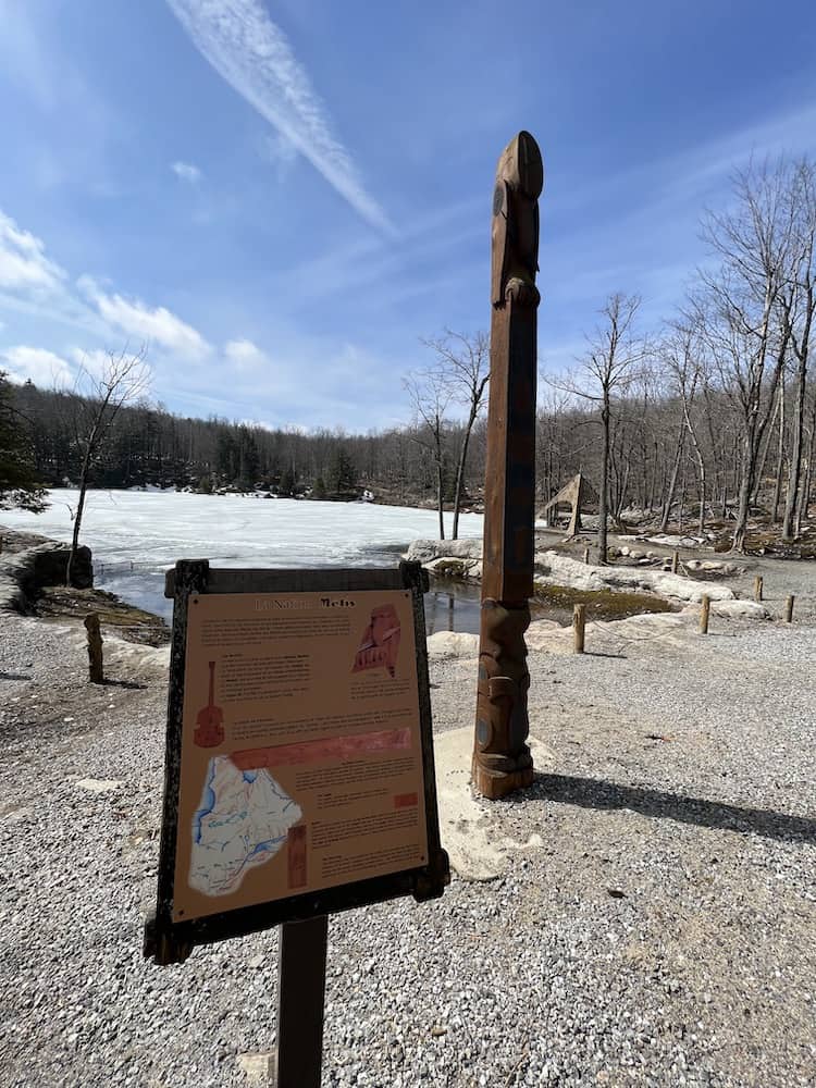 totem pole and a plaque with First Nations information on one tribe from Quebec in front of Beaver Lake 