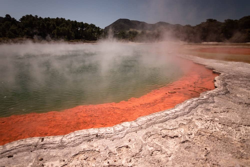 When is winter in New Zealand? (& Should You Visit?) 10 Rotorua hot pool with geothermic waters that are steaming. Green water next to orange-y rocks.