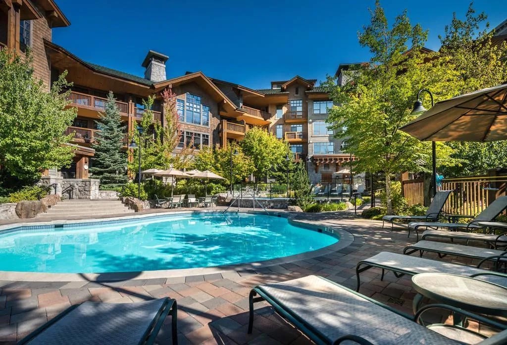 11 Best Resorts in Whistler (2024 Guide) 7 Summer at the First Tracks Lodge resort in Whistler with the wooden lodge in the background and an outdoor pool in the foreground.