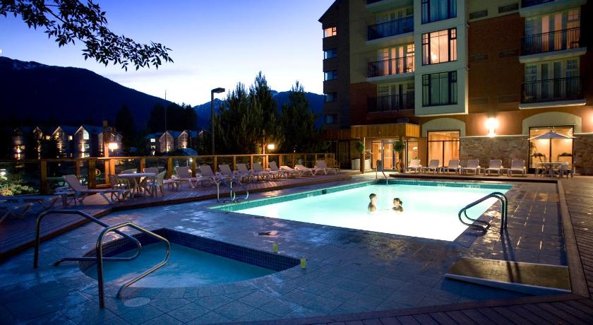 11 Best Resorts in Whistler (2024 Guide) 2 Outdoor pool lit up at night at the Hilton Whistler Resort & Spa with two people swimming