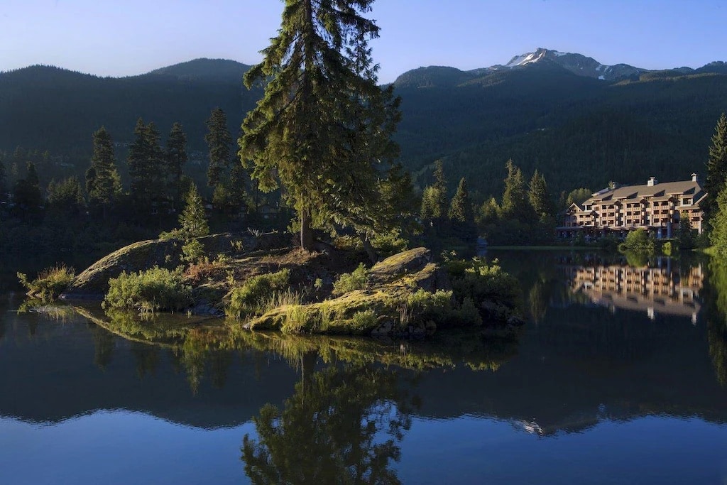 11 Best Resorts in Whistler (2024 Guide) 8 Nita Lake with green trees surrounding it and the lodge on the shore with the Whistler mountains in the background.