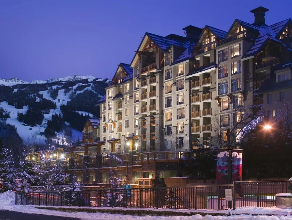 11 Best Resorts in Whistler (2024 Guide) 5 Pan Pacific Whistler Villag Resort at night in winter with white christmas lights around the exterior.