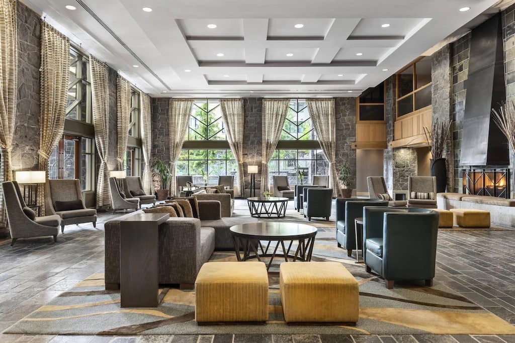11 Best Resorts in Whistler (2024 Guide) 10 Interior of the Westin Resort in Whistler with stone walls and yellow and grey couches.