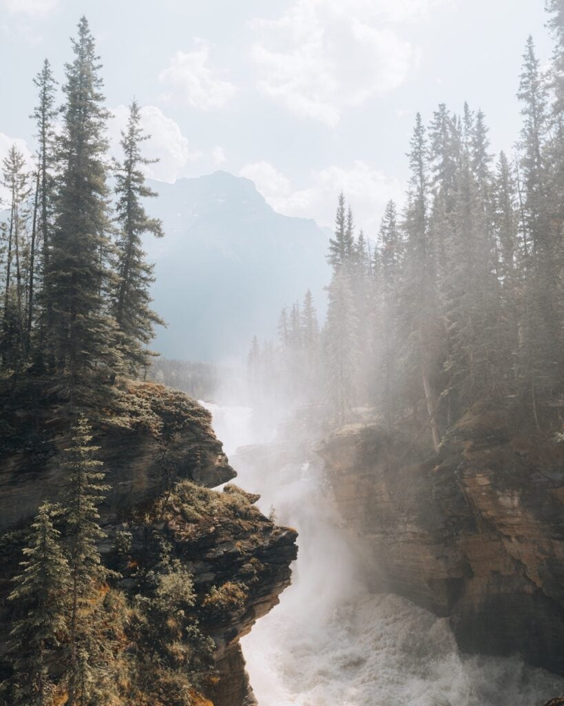 Banff National Park Itinerary: 1, 3, and 5 Day Guides 11 The wild Athabasca Waterfalls in between rock mountains on a sunny day in Banff.