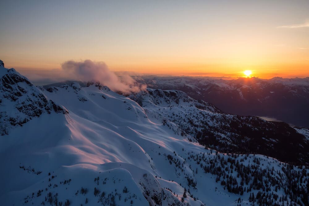 5 Best Banff Helicopter Tours (2024) 2 Beautiful view from a helicopter tour in Banff showing the sunrise beneath the scenic snowy mountains.