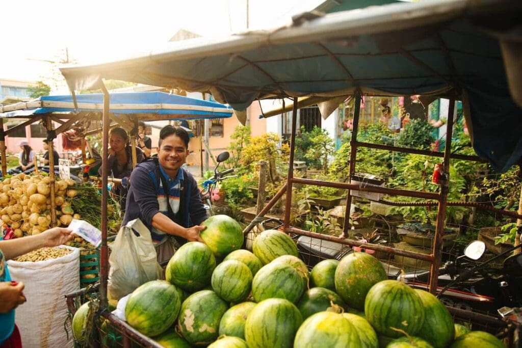 21 Pros and Cons of Living in the Philippines in 2024 1 A fruit vendor selling watermelons in one of the wet markets in the Philippines - fruit is very affordable and one of the pros of living in the Philippines.