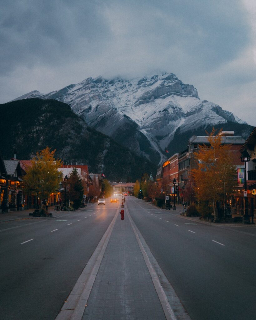 Banff National Park Itinerary: 1, 3, and 5 Day Guides 9 The main street of Banff Town, a great stop when you're visiting Banff NP, with shops on the sides and a snowy mountain right in front.