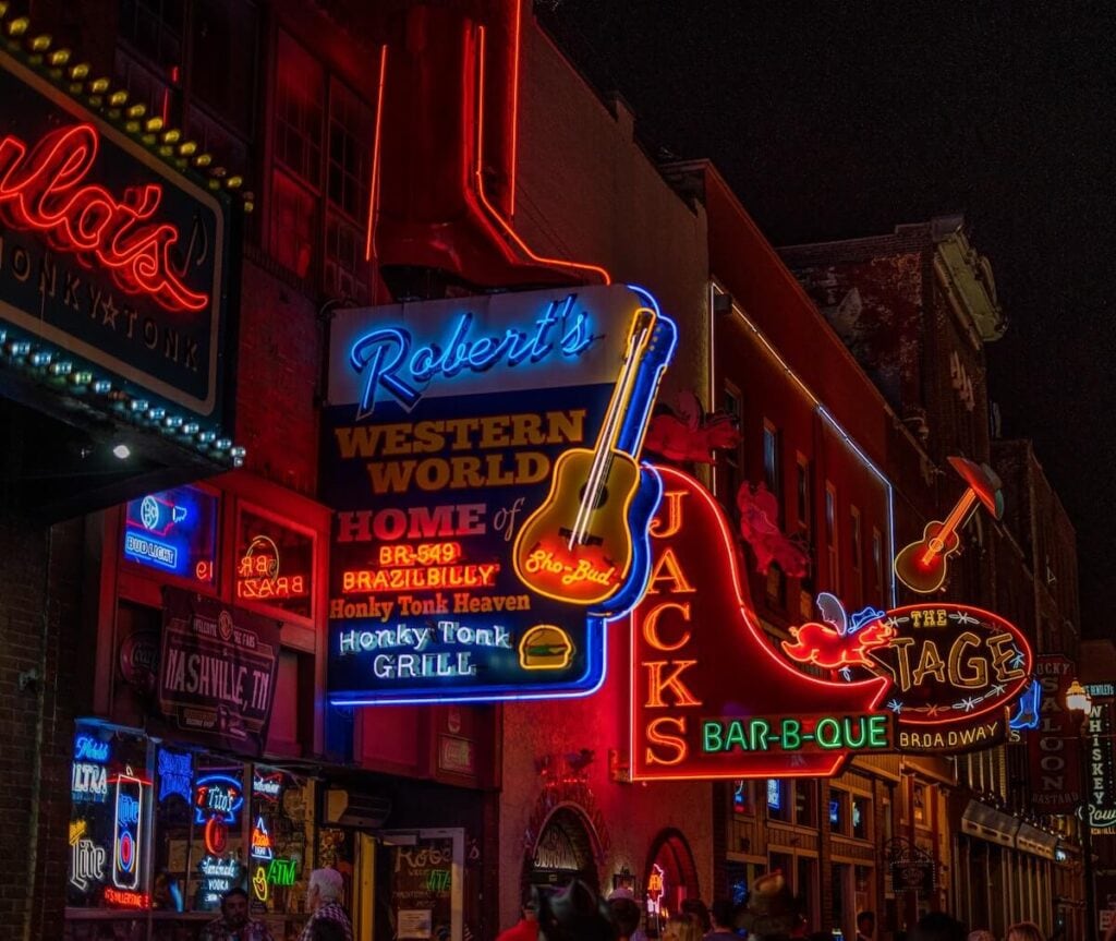 23 Pros and Cons of Living in Nashville in 2024 5 Neon signboards of bar restaurants in Nashville on a beautiful night - one of the big perks of living in Nashville. Barbecue!