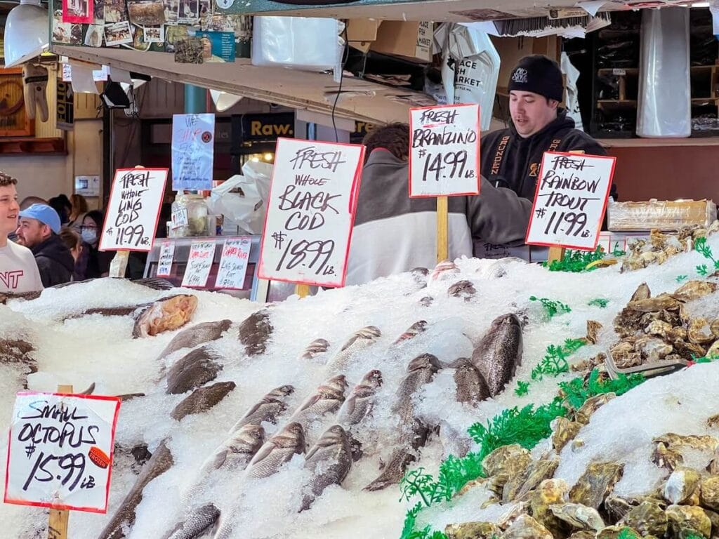 23 Pros and Cons of Living in Seattle in 2024 4 A photo captured in one of the wet markets in Seattle, focusing on various types of fish submerged in crushed ice with prices.
