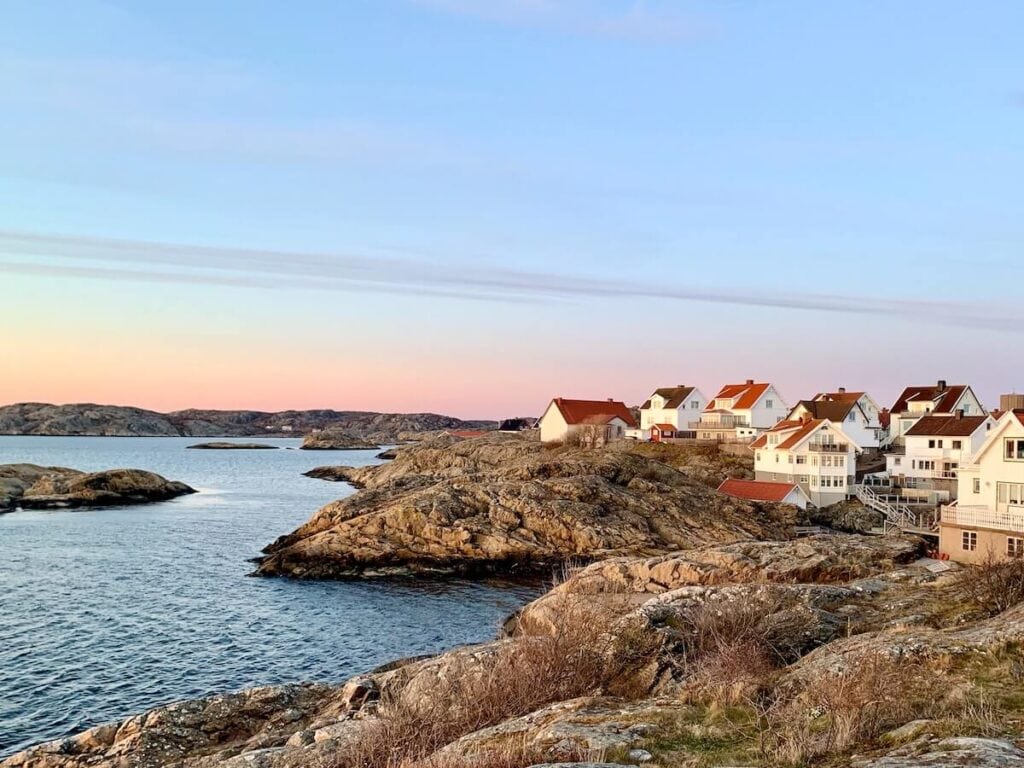 27 Pros and Cons of Living in Sweden in 2024 3 Few white houses with orange roofs beside a lake in Sweden on a windy day - it's not easy to find a house which is definitely a con of wanting to move there.