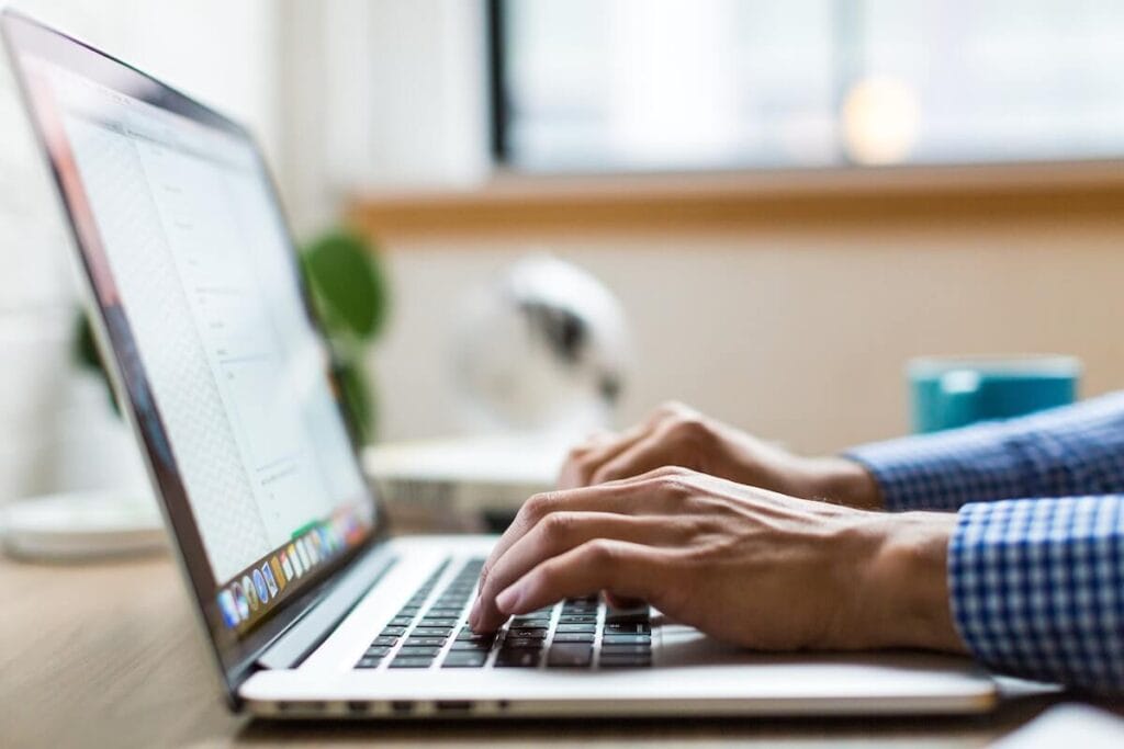 25 Pros and Cons of Living in Costa Rica in 2024 13 Man's hands typing on a laptop while working as a digtial nomad in Costa Rica