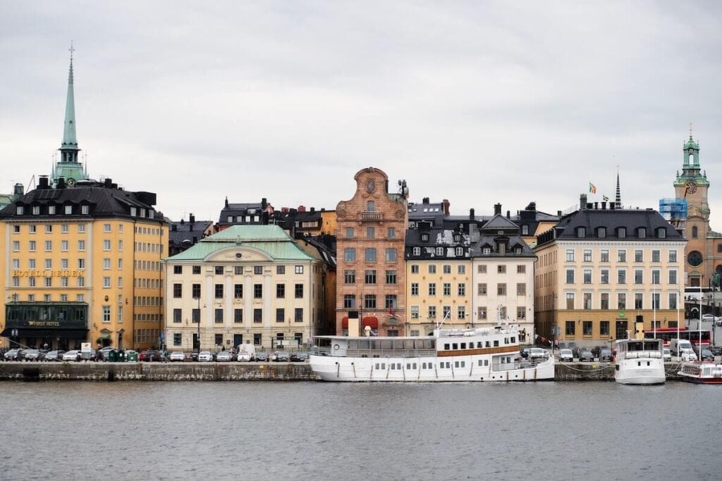 27 Pros and Cons of Living in Sweden in 2024 4 Beautiful buildings in Sweden in front of the dock with a number of boats on the river.