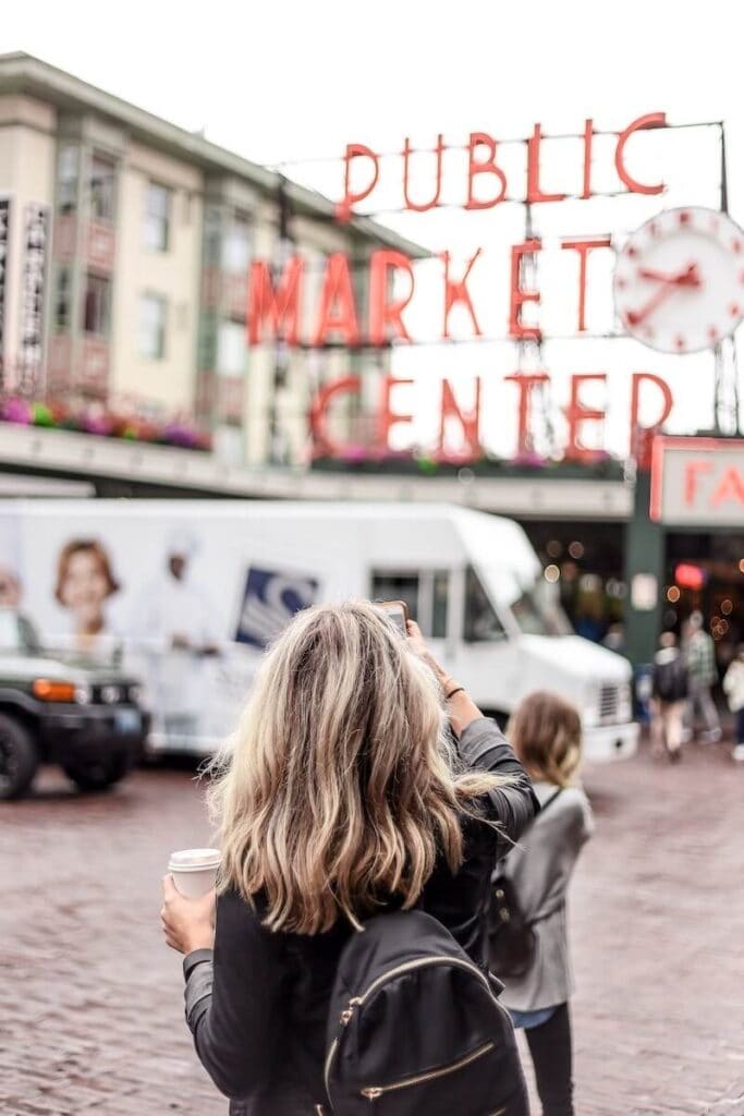 23 Pros and Cons of Living in Washington State in 2024 5 A woman is standing in front of the entrance of a public market in Washington State.