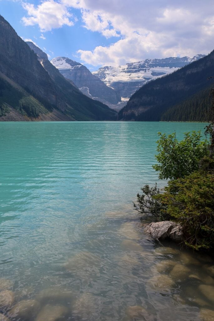Where to Stay in Lake Louise Canada: 14 Best Hotels (2024) 4 A lake with crystal clear water near mountain ranges and trees.