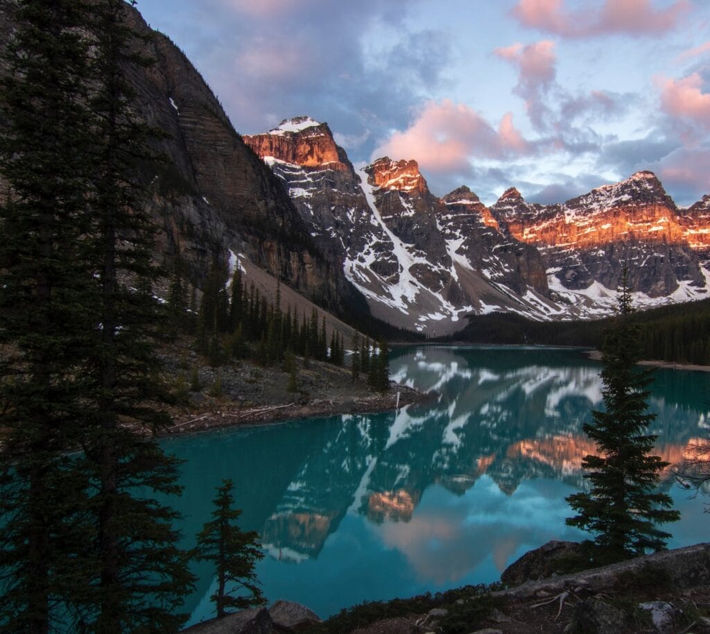 Where to Stay in Lake Louise Canada: 14 Best Hotels (2024) 9 A lake surrounded by mountain and trees under cloudy sky