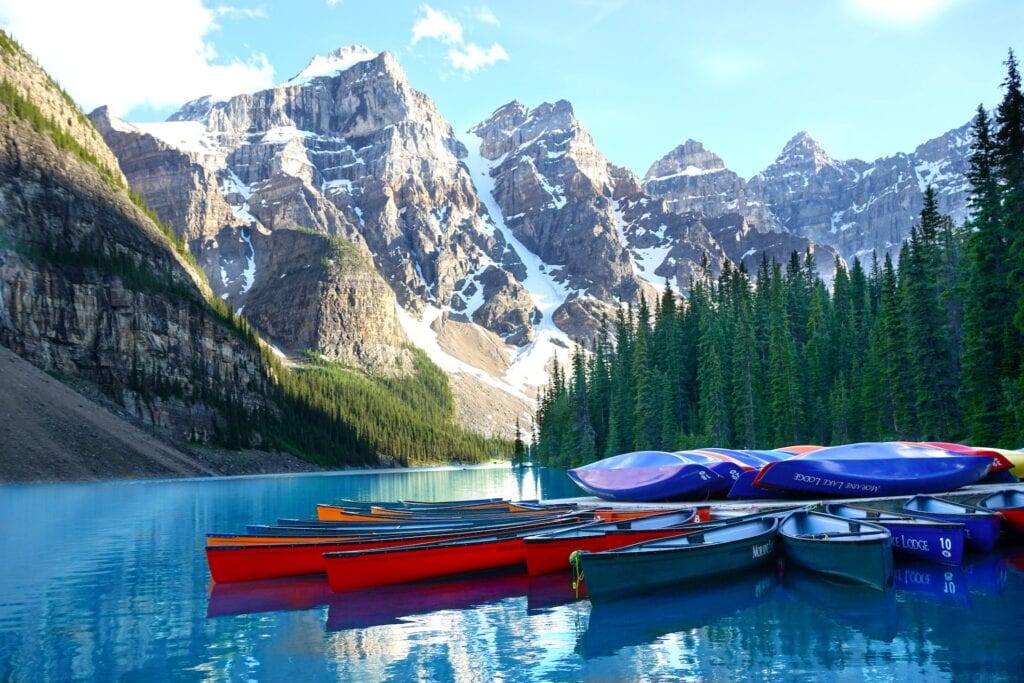 Where to Stay in Lake Louise Canada: 14 Best Hotels (2024) 10 Assorted color boats sitting on top of a lake near a mountain and trees