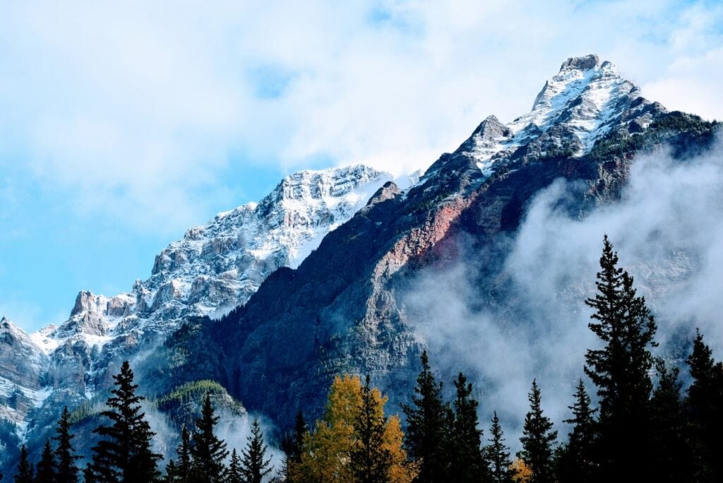 12 Best Jasper Helicopter Tours (2024) 12 A photo of large mountains covered by snow with green trees below. This is the Mount Robson where one of the best Jasper Helicopter Tours fly over.