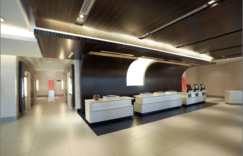12 Best Toronto Hotels With Rooftop Pools (2024) 9 A white front desk with three touchscreen monitors at the Hilton Toronto Hotel. The room is well-lit highlighting the beige and black colored tiles.