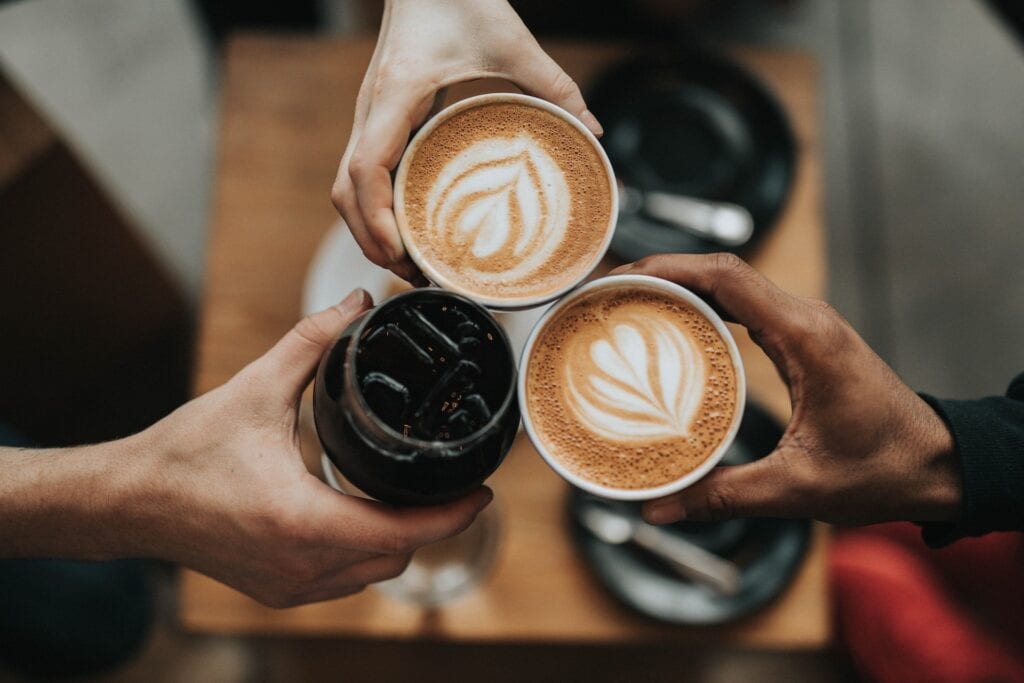 23 Best Reasons to Be Living in Melbourne in 2024 2 Two cups of art lattes and one cup of black coffee clinked together. Living in Melbourne gives you access to incredible and irresistible coffee.