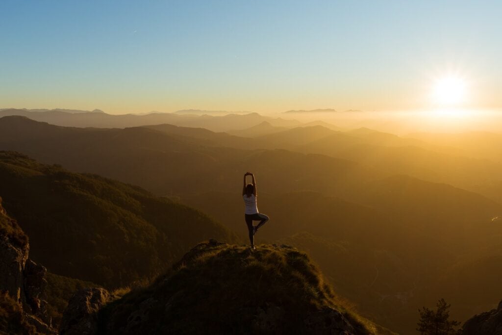 12 Best Jasper Helicopter Tours (2024) 10 A woman doing a yoga pose on a mountaintop during the sunrise. Yoga and meditation is included in one of the best Jasper Helicopter Tours.