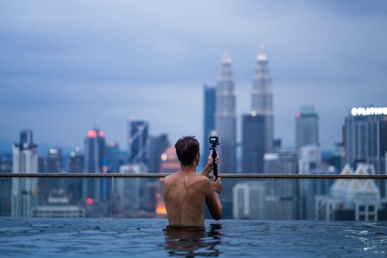 12 Best Toronto Hotels With Rooftop Pools (2024) 5 Man looking out the skyscrapers from a rooftop pool during the afternoon
