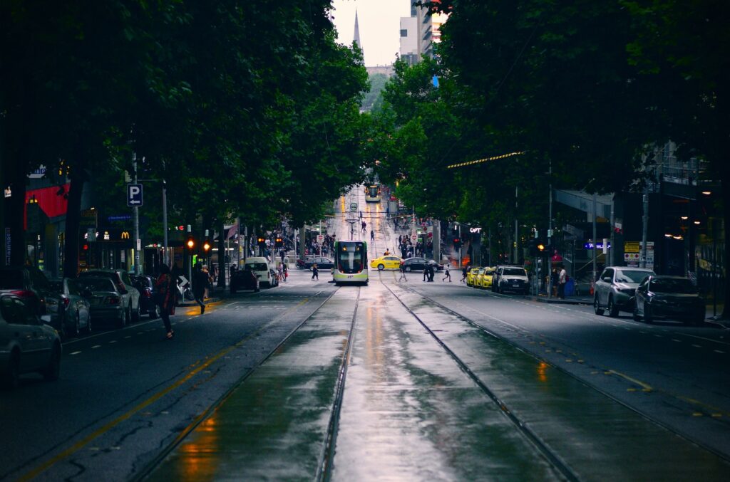 23 Best Reasons to Be Living in Melbourne in 2024 7 A photo of a yellow and black bus on an asphalt rode with busy people on the sidewalks. This is in Melbourne, Australia.