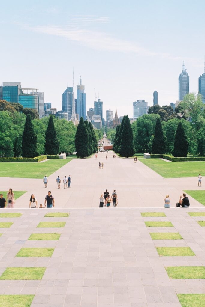 23 Best Reasons to Be Living in Melbourne in 2024 1 People strolling in a park with green grass fields and well-maintained trees. This is the the Shrine of Remembrance - a park in Melbourne