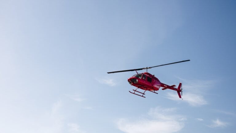 3 Best Helicopter Tours in Vancouver + Other Air Tours 2024 8 Red Helicopter flying in blue skies during a clear day. This is the view from below the BC backcountry helicopter Tour, a helicopter tour in Vancouver.