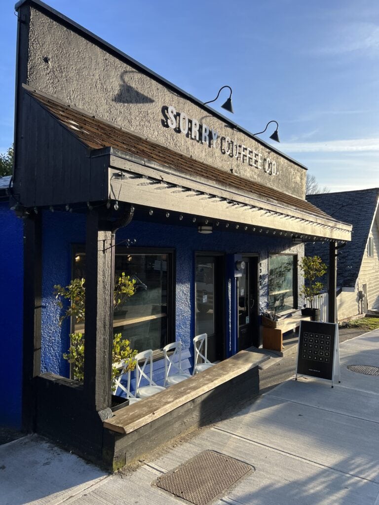 23 Best Things to Do in Deep Cove, BC 2024 18 Sorry Coffee Co exterior with indigo walls and white patio seating out front in Deep Cove.