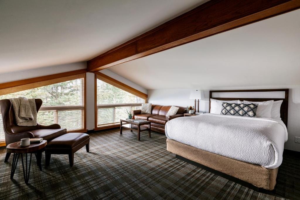 Where to Stay Near Jasper National Park: 16 Best Hotels 13 A large bed with white sheets beside brown leather couch. A single sofa beside a coffee table can also be seen facing the bed. A large window is also seen beside the couch that lets guests enjoy the view of the Pyramid Lake resort in Jasper.