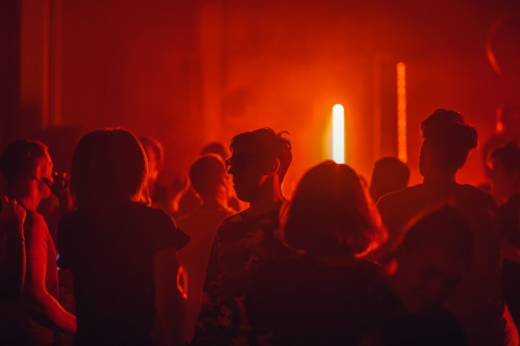 23 Top Pros and Cons of Living in Miami in 2024 9 Several people in a red-lit room partying. One of the pros of living in Miami is its Hip Nightlife Scene.