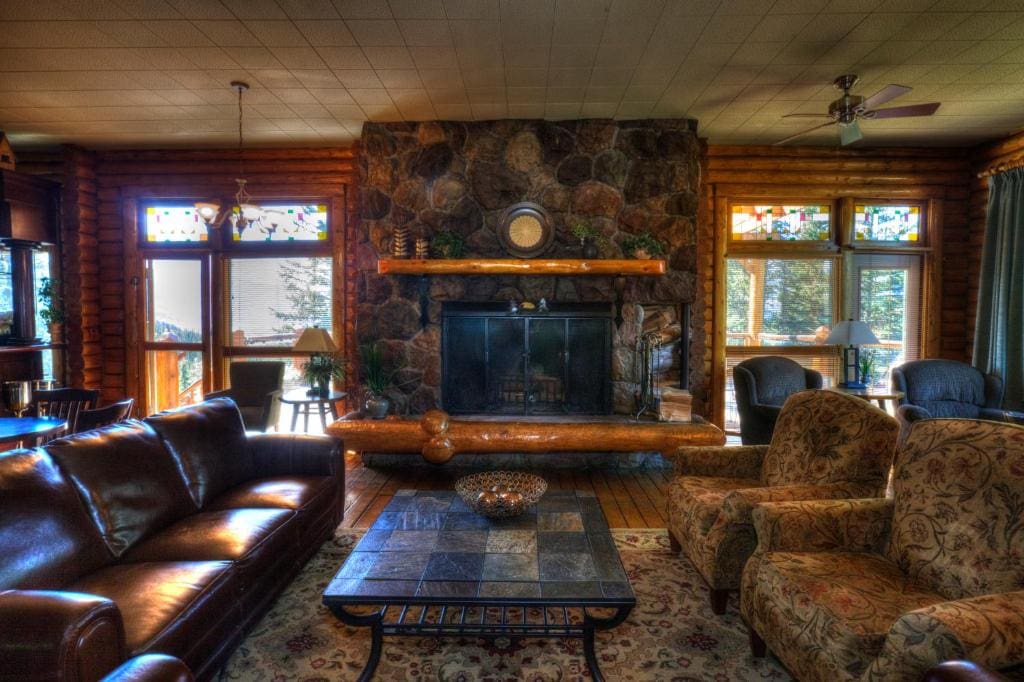 Where to Stay Near Jasper National Park: 16 Best Hotels 15 A leather couch facing two single patterned sofas in the middle of a room with wooden walls and floors. A fireplace and a coffee table can be seen in the middle of the chairs. This is the Overlander Mountain Lodge in Jasper National Park