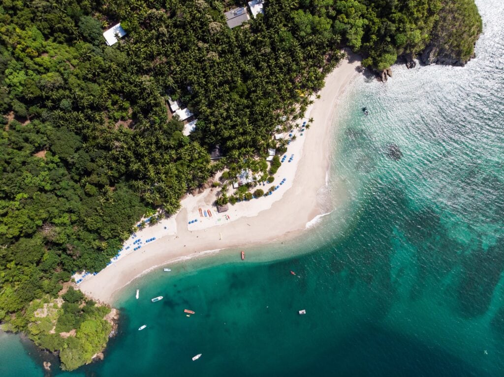 25 Pros and Cons of Living in Costa Rica in 2024 3 Aerial view of the Costa Rican beach with teal waters and white sand beaches before the green forest.
