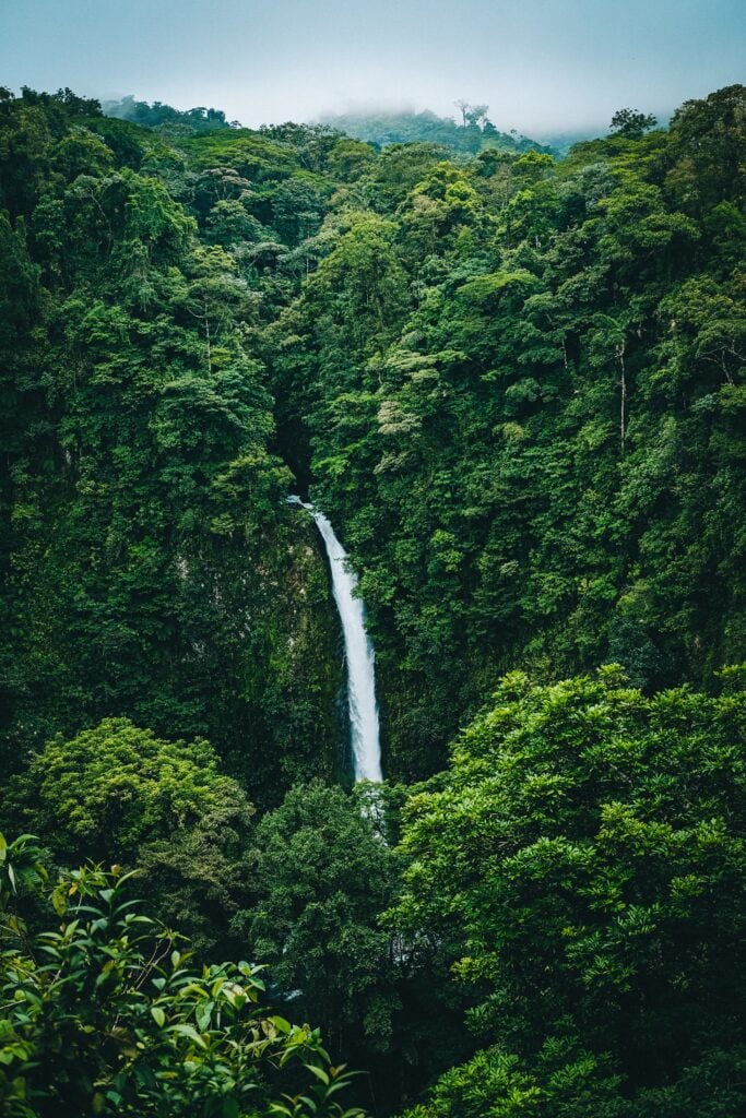 25 Pros and Cons of Living in Costa Rica in 2024 15 Overhead view of a costa rican waterfall falling through a dense green jungle