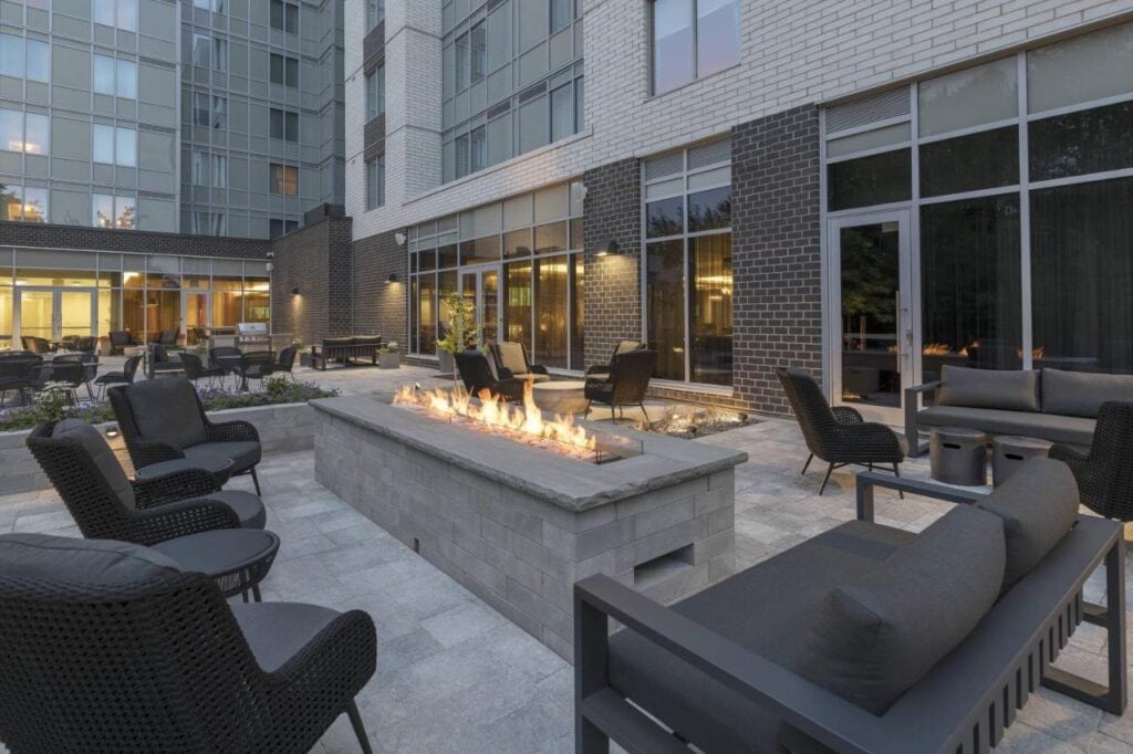 Where to Stay in Halifax: 17 Best Hotels in 2024 14 A unique fireplace made out of gray bricks and limestone placed in the middle of black couches and chairs. This is the outdoor lounge of the Courtyard by Marriot in Dartmouth, Halifax.