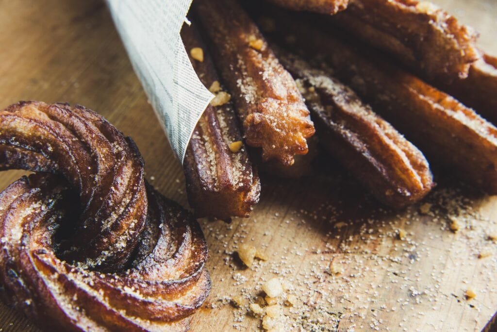 15 Pros And Cons Of Living In Madrid (By an Expat) 4 A photo of long stick-like pastry coated with sugar and nuts. These are called churros, a famous delicacy of Madrid.