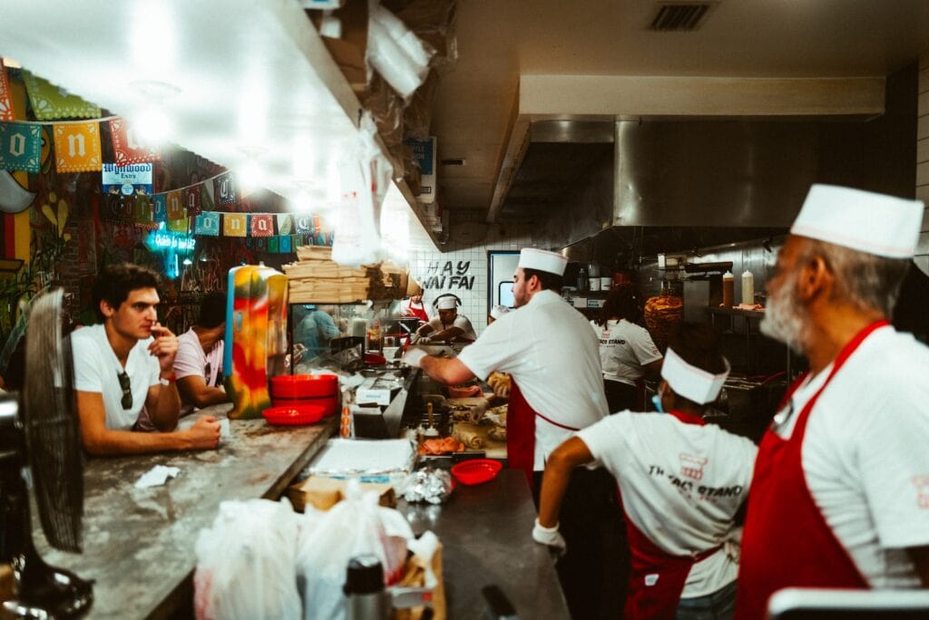 23 Top Pros and Cons of Living in Miami in 2024 10 Three people cooking food in front of customers. One good thing about living in Miami is its Vibant and Diverse Food Scene.