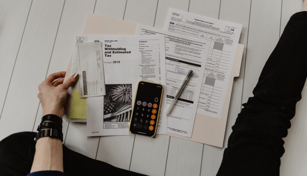 27 Pros and Cons of Living in Tennessee in 2024 1 Person holding tax papers with a calculator on top of a white desk. One of the pros of living in Tennessee is its no income tax policy.